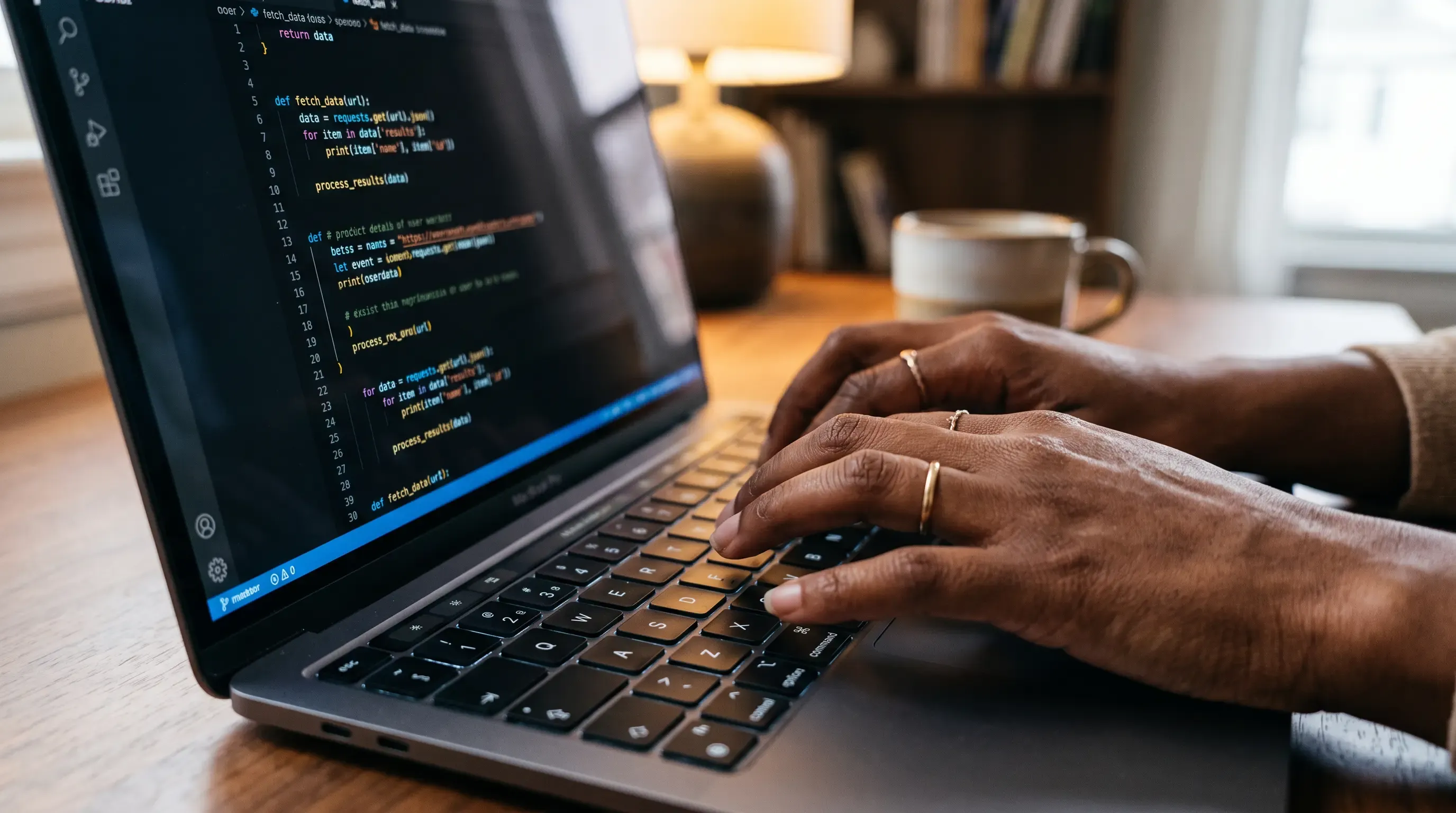 A close up of dark skin hands typing code onto a laptop.